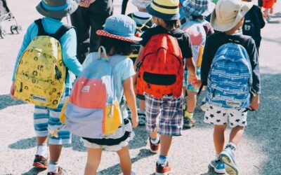 group of people wearing white and orange backpacks walking on gray concrete pavement during daytime