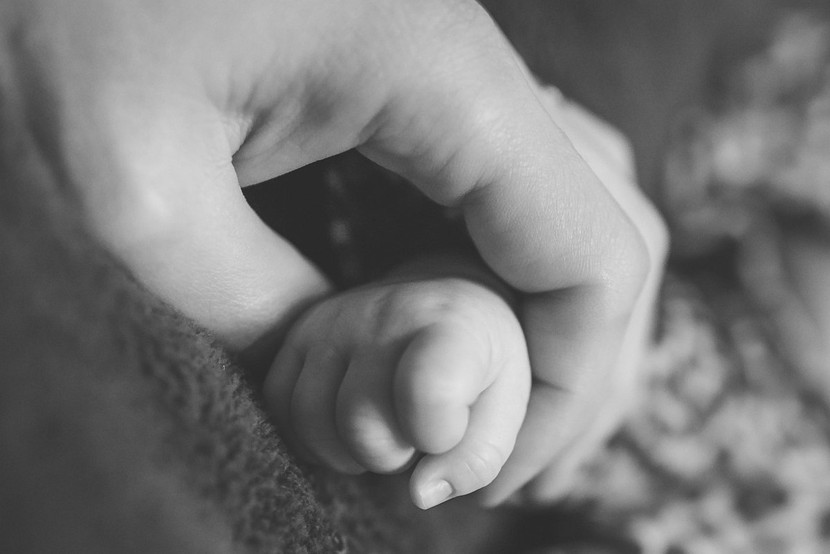 Une main adulte serre doucement une petite main bébé