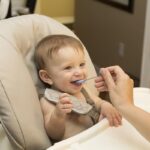 Un bébé souriant mange une bouchée avec une cuillère