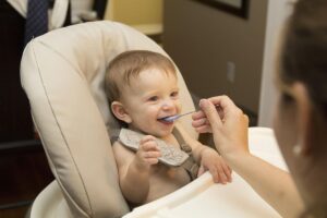 Un bébé souriant mange une bouchée avec une cuillère
