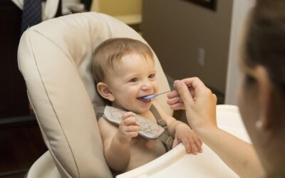 Un bébé souriant mange une bouchée avec une cuillère