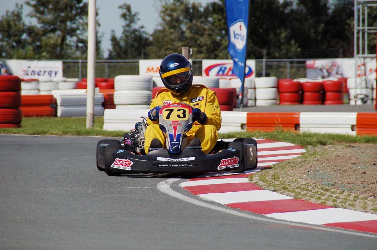 Un coureur en karting jaune conduit sa voiture sur un virage de circuit