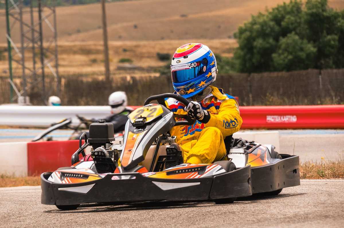 Un coureur en karting porte un casque coloré et pilote une voiture rouge