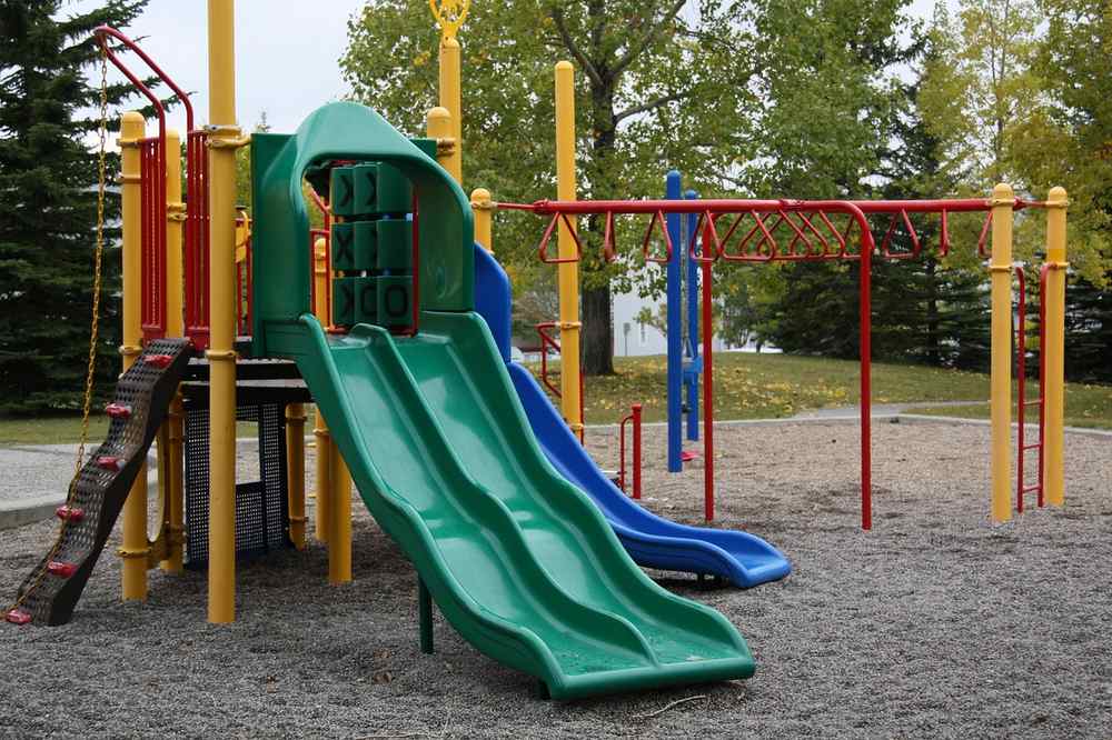 Un parc d juegos avec glissière verte, structures colorées et sol sableux Un parc d juegos avec glissière verte, structures colorées et sol sableux