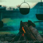 Feu de camp avec trois casseroles suspendues en pierre et bois