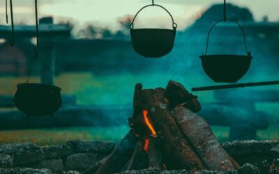 Feu de camp avec trois casseroles suspendues en pierre et bois