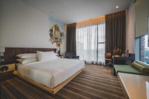 Une chambre moderne avec lit king, canapé vert, bureau et vue grande fenêtre
