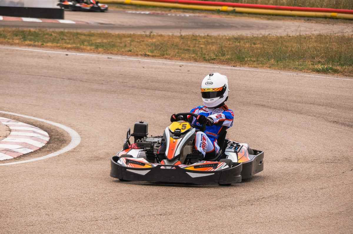 Un pilote en karting tourne à gauche sur un circuit asphalté Un pilote en karting tourne à gauche sur un circuit asphalté