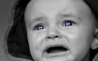 Un bébé en capuche pleure, une larme coule, ses yeux sont bleus