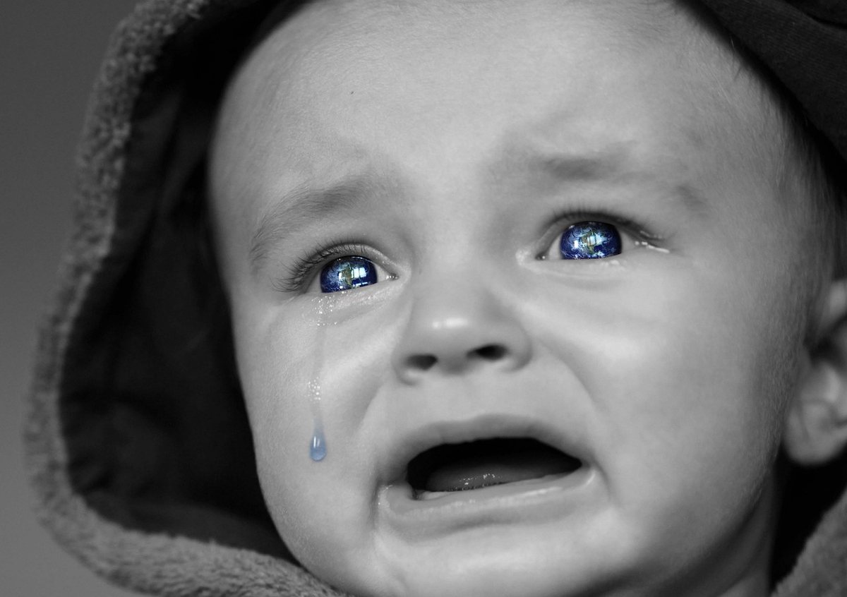 Un bébé en capuche pleure, une larme coule, ses yeux sont bleus