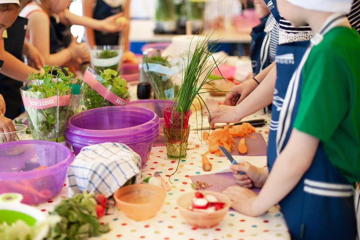 Des enfants en tablier préparent des légumes et fruits sur une table Des enfants en tablier préparent des légumes et fruits sur une table