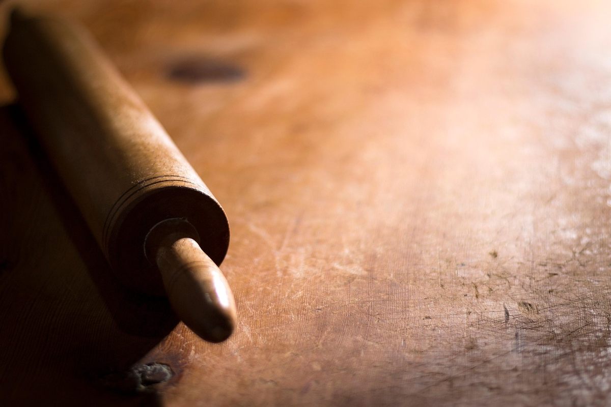 Rouleau à pâtisserie en bois posé sur une table rustique Rouleau à pâtisserie en bois posé sur une table rustique