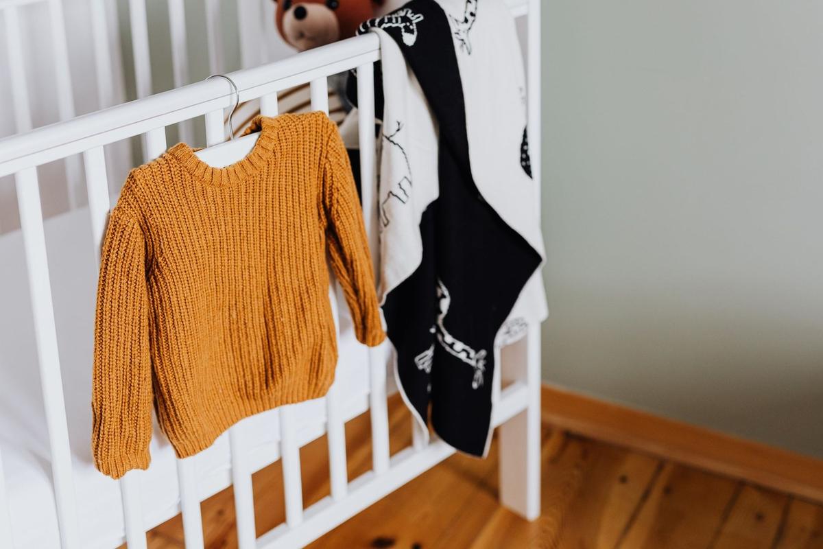 Berceau avec pull orange et plaid noir et blanc, ours en peluche