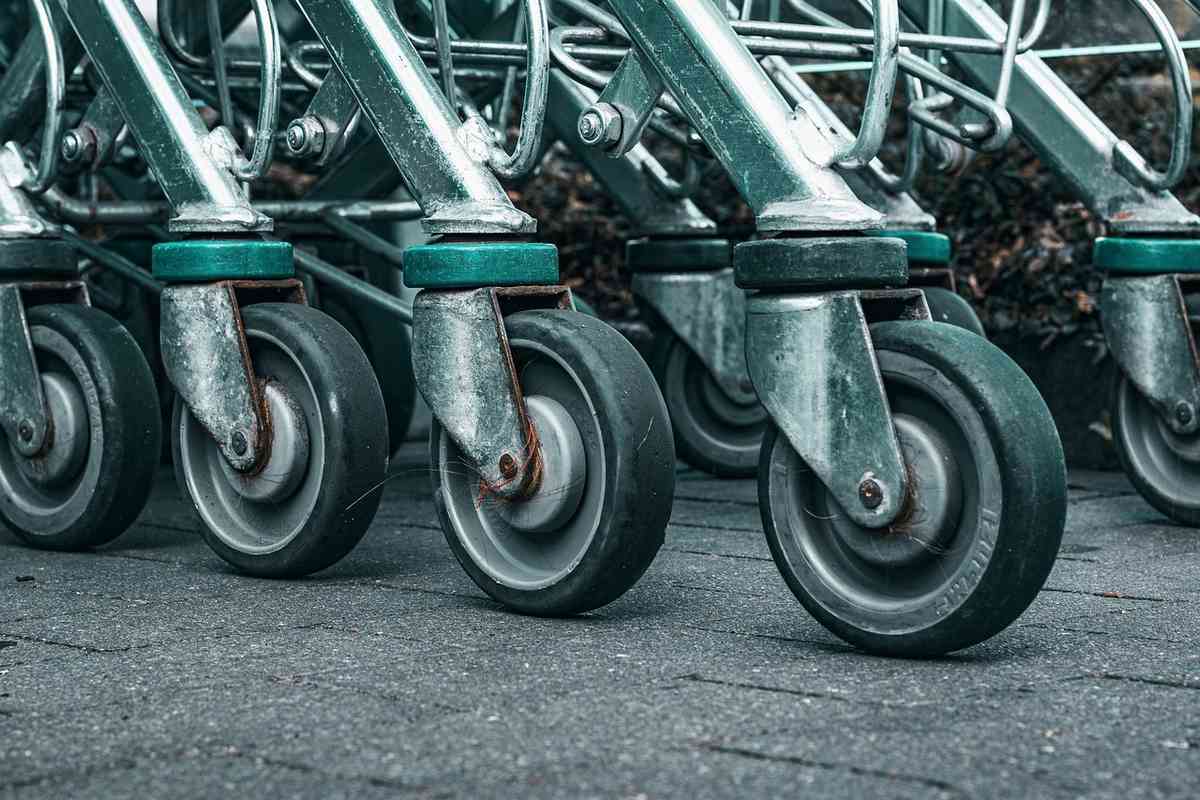 Plusieurs chariots métalliques alignés, leurs roues sur le béton