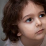 Un enfant aux cheveux bouclés regarde en haut, visage tourné légèrement