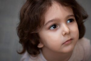 Un enfant aux cheveux bouclés regarde en haut, visage tourné légèrement