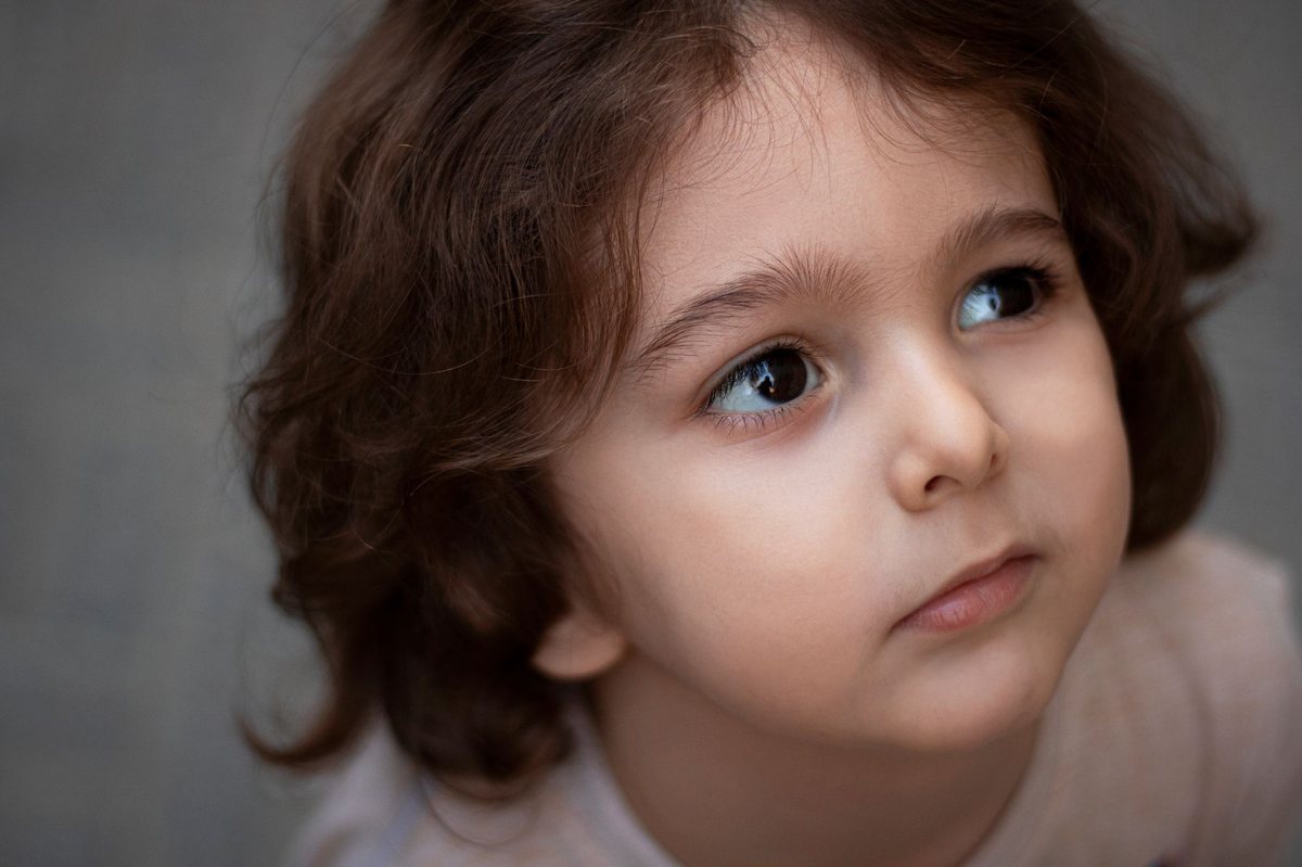 Un enfant aux cheveux bouclés regarde en haut, visage tourné légèrement
