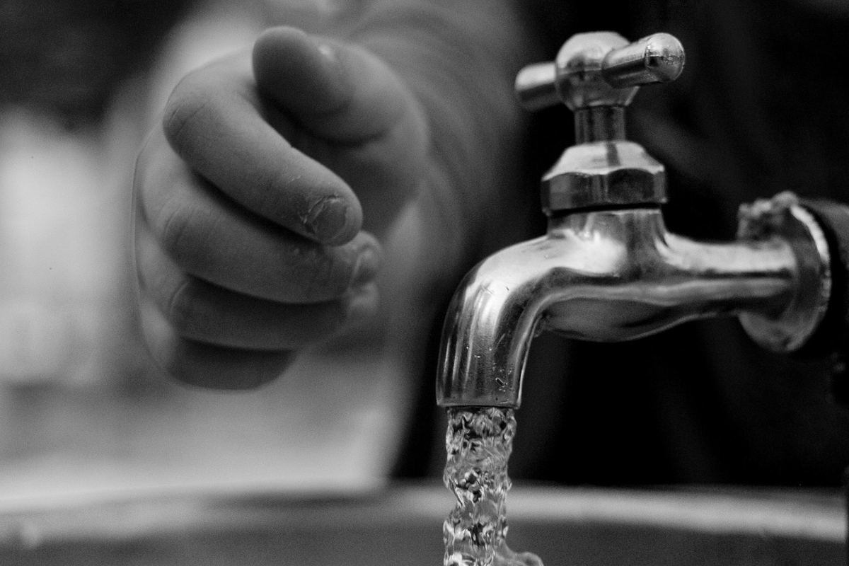 Une main ferme le robinet d'eau qui coule dans l'évier