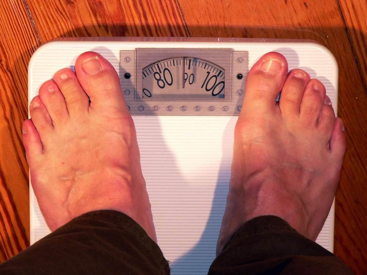 Pieds nus posés sur une balance à cadran, sol en bois