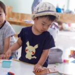Enfants asiatiques manipulant des jouets sur une table dans une pièce lumineuse