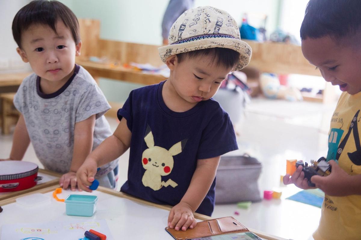 Enfants asiatiques manipulant des jouets sur une table dans une pièce lumineuse