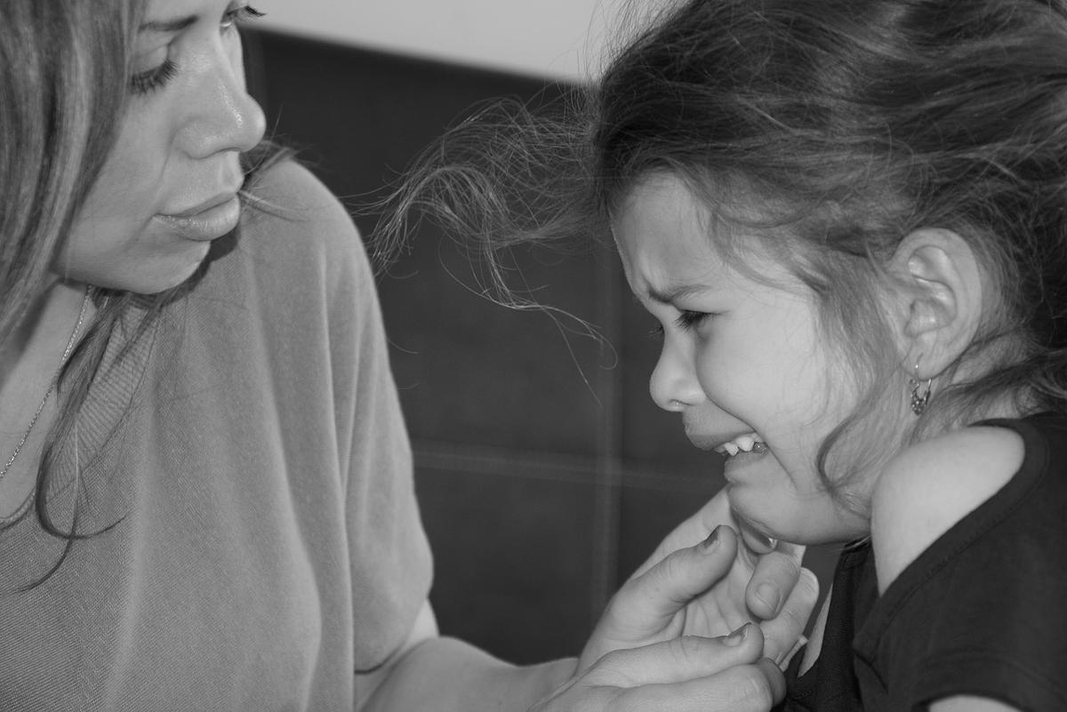 Une femme réconforte une fillette en larmes, leurs mains se touchent Une femme réconforte une fillette en larmes, leurs mains se touchent